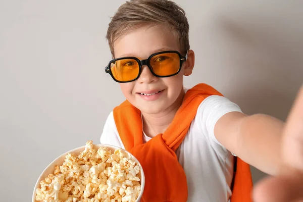 戴眼镜的小男孩 背着一桶美味的爆米花 带着浅色背景的自拍 — 图库照片