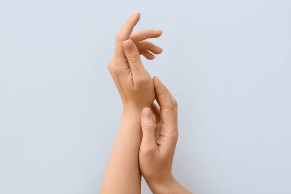 Женские руки с нежным маникюром на сером фоне