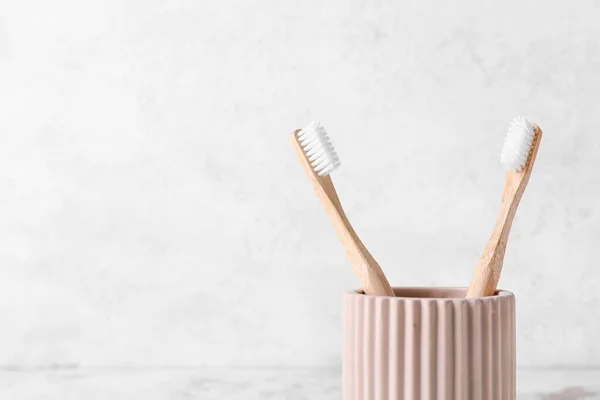 Holder with wooden toothbrushes on light background, closeup