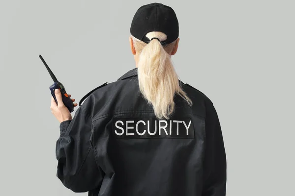 Female security guard on grey background, back view