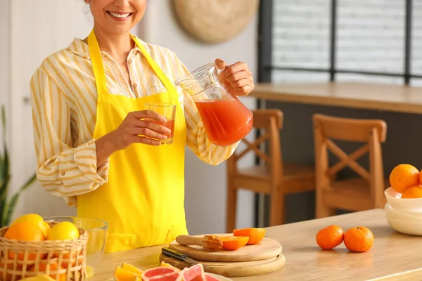 在厨房里放了新鲜的自制柑橘汁的年轻女人 — 图库照片