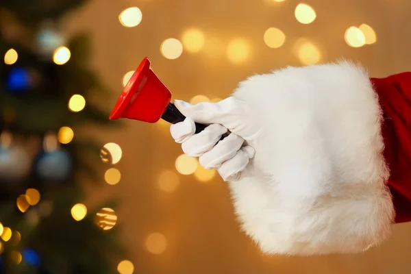 Kerstman Hand Met Kerstbel Tegen Wazig Licht — Stockfoto