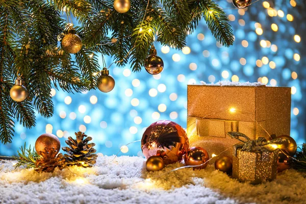 モミの木の枝 ギフトボックスや色の背景に雪の上に輝く光を持つ美しいクリスマスの組成 — ストック写真