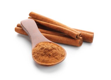 Doğal tarçın tozlu kaşık ve beyaz arka planda çubuklar