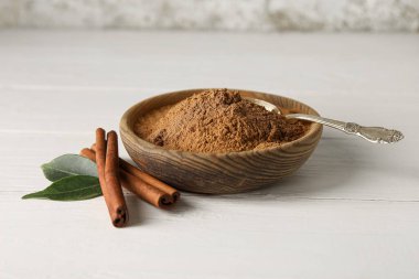 Tarçın tozlu kase ve beyaz ahşap arka planda çubuklar