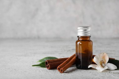 Tarçın özü yağ ve ışık arkaplanına yapışmış bir şişe.