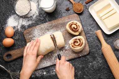 Siyah arkaplanda tarçınlı çörek hazırlayan kadın