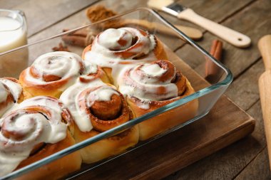 Ahşap arka planda kremalı lezzetli tarçınlı börek pişirme, yakın plan.