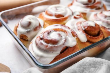 Beyaz arka planda kremalı lezzetli tarçınlı rulo pişirme, yakın plan.