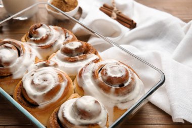 Ahşap arka planda kremalı lezzetli tarçınlı börek pişirme, yakın plan.