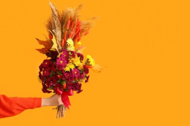 Renkli arka planda güzel bir sonbahar buketi olan kadın eli, yakın plan.