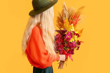 Şapkalı kadın arka planda güzel bir buket tutuyor.