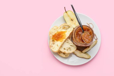 Cam kavanoz armut reçeli ve pembe arka planda ekmek.