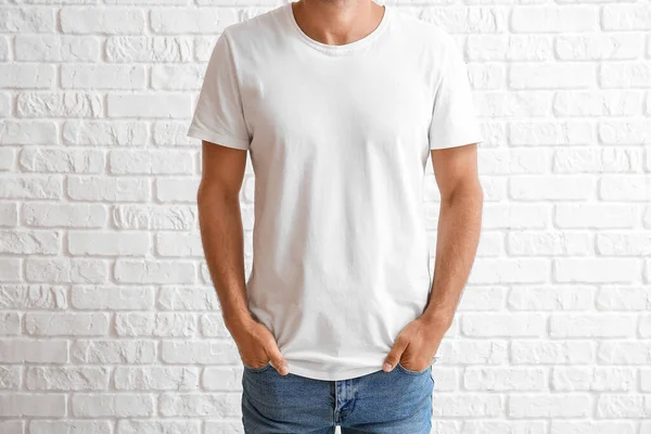 ハンサムな若いです男でスタイリッシュなTシャツ上の白いレンガの背景 — ストック写真