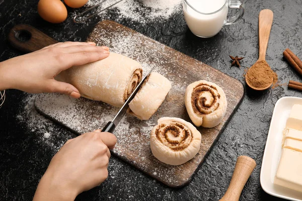 Siyah arkaplanda tarçınlı çörek hazırlayan kadın