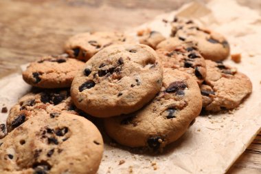 Ahşap arka planda ev yapımı lezzetli kurabiyeler olan parşömen, yakın plan.