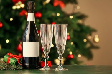 Bulanık arka planda bir şişe şampanya ve Noel hediyesi kutusu.