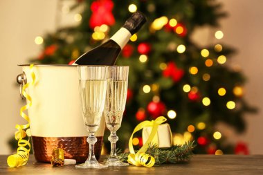 Bulanık arka planda şampanya, bardak ve Noel dekoruyla dolu bir kova.