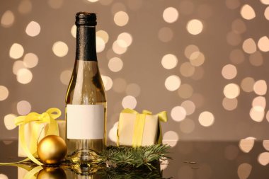 Bir şişe şampanya, hediye kutuları ve arka planda bulanık bir Noel süsü.