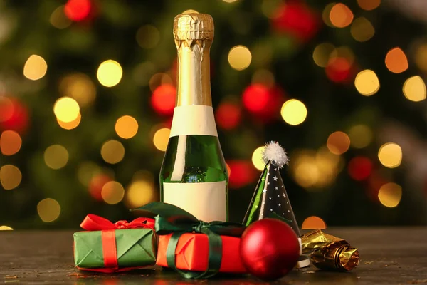 ギフトボックスとぼやけた背景にテーブルの上のクリスマスの装飾を持つシャンパンのボトル — ストック写真