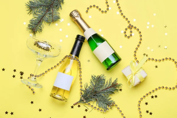 İçinde şampanya şişeleri ve sarı arka planda Noel süsü olan kompozisyon