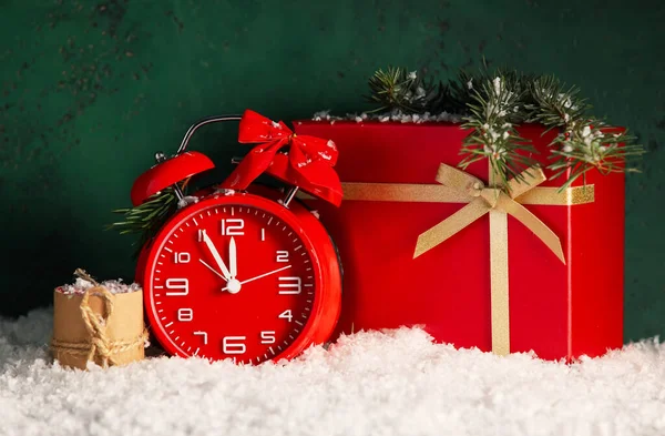 緑の背景に雪の上の目覚まし時計 クリスマスプレゼントやキャンドルと組成 — ストック写真
