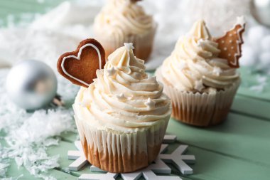 Yeşil ahşap arka planda Noel dekoru olan lezzetli kekler.