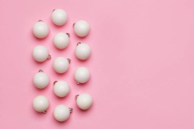 Pembe arka planda beyaz Noel topları