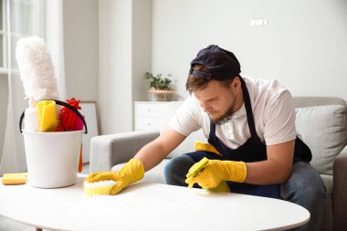 Evde sünger temizleme masası olan genç bir adam.