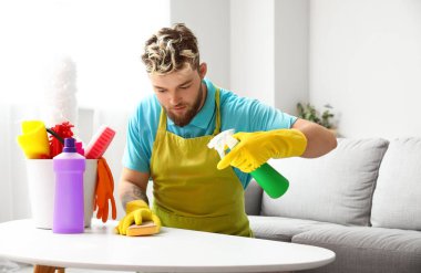 Evdeki masaları temizleyen yakışıklı genç adam.