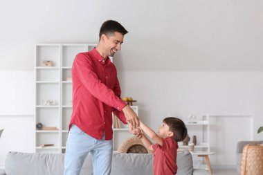 Bir adam ve küçük oğlu evde dans ediyor.