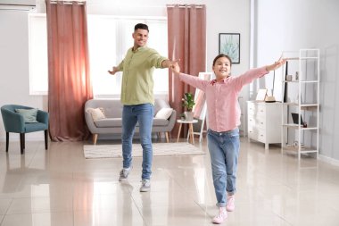 Bir adam ve küçük kızı evde dans ediyor.