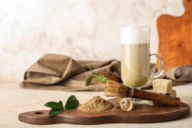 Hafif arka planda bir bardak hojicha latte, chasen, toz ve marshmallow ile ahşap tahta tahta.