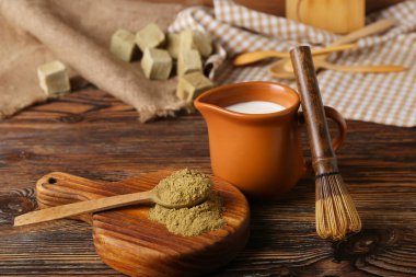 Tahta, hojicha tozu, bir sürahi süt ve ahşap arka planda chasen.