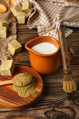 Tahta, hojicha tozu, bir sürahi süt ve ahşap arka planda chasen.