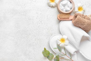 Ayak masajı için banyo malzemeleri ve hafif arka planda terlikler.