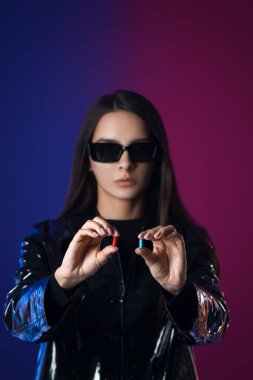 Siyah arka planda mavi ve kırmızı hapları olan bir kadın. Seçim kavramı