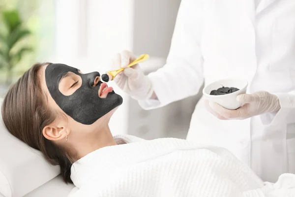 美容院美容师在女性脸上涂活性炭面罩 — 图库照片