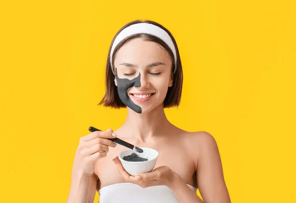 Wanita Muda Menerapkan Diaktifkan Arang Masker Wajahnya Terhadap Latar Belakang — Stok Foto