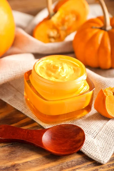 Jar with natural pumpkin mask and spoon on wooden background, closeup