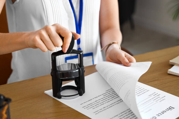 Женщина-нотариус публично прикрепляет печать к документу в офисе, крупным планом
