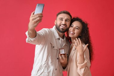 Renkli arka planda selfie çeken nişanlı genç çift