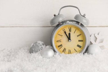 Çalar saat ve karda hafif ahşap arka planda Noel süslemeleri