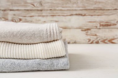 Hafif ahşap arka planda farklı rahat süveterler yığını