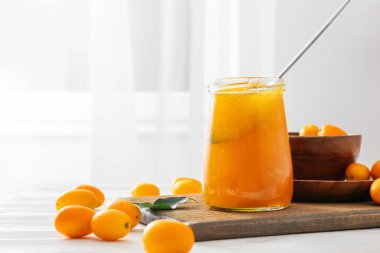 Kavanoz dolusu lezzetli kumkat reçeli ve mutfak masasında taze meyve.