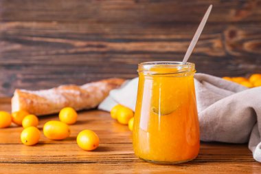 Bir kavanoz lezzetli kumkat reçeli ve ahşap zemin üzerinde taze meyveler.