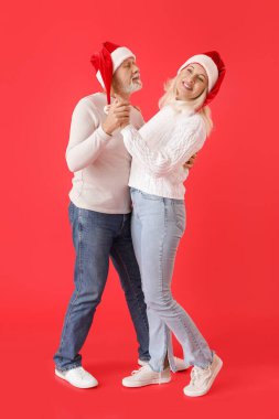 Mutlu dans eden olgun bir çift Noel Baba şapkası takıyor.