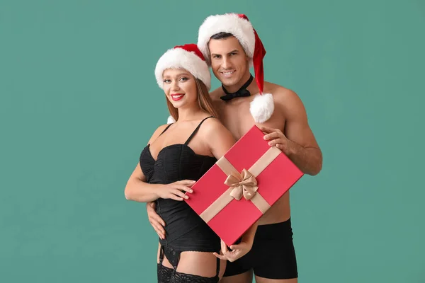 セクシー若いですカップルで下着ととともにクリスマスギフト上の色の背景 — ストック写真