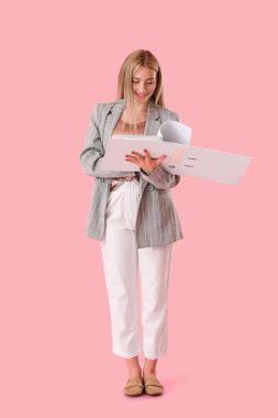 Pembe arka planda açık klasörü olan güzel bir genç kadın.