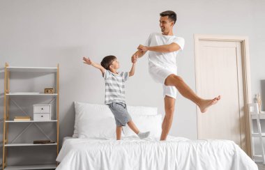 Bir adam ve küçük oğlu yatak odasında dans ediyor.